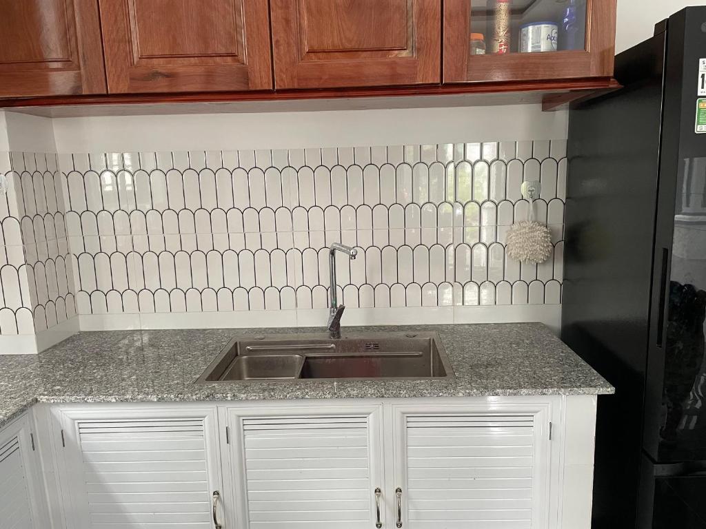 - un comptoir de cuisine avec évier et carrelage blanc dans l'établissement Habi Homestay Doc Let, 