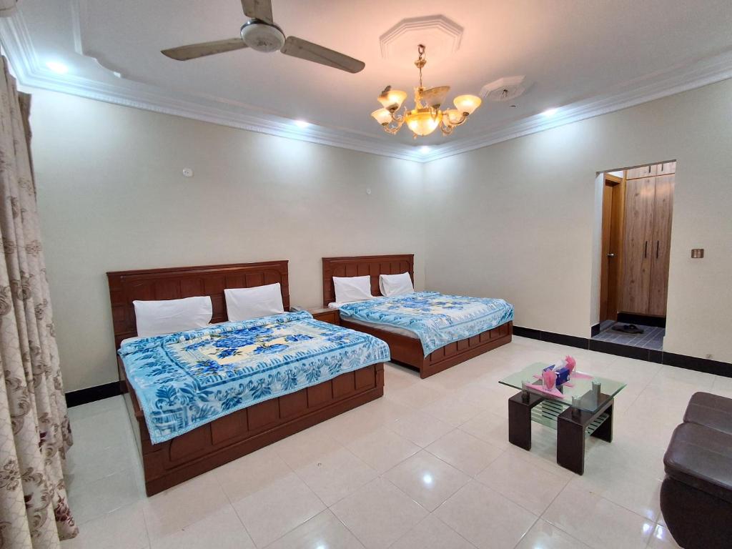 カラチにあるFamily Rose Guest House Millenniumのベッド2台と天井ファン付きの寝室