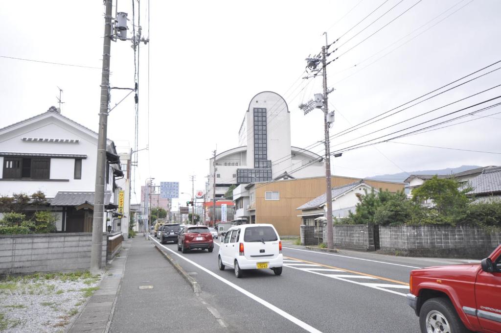 Ein weißes Auto fährt eine Straße mit Gebäuden entlang in der Unterkunft Hotel Tamai in Aki