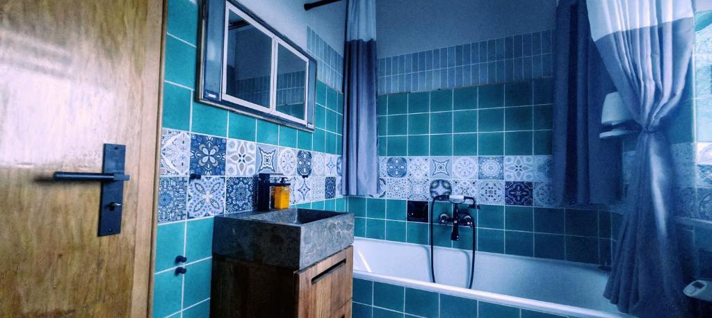 a bathroom with a sink and a tub with blue tiles at Ferienhaus Villa Zauberblick am Rennsteig Frankenwald in Ludwigsstadt