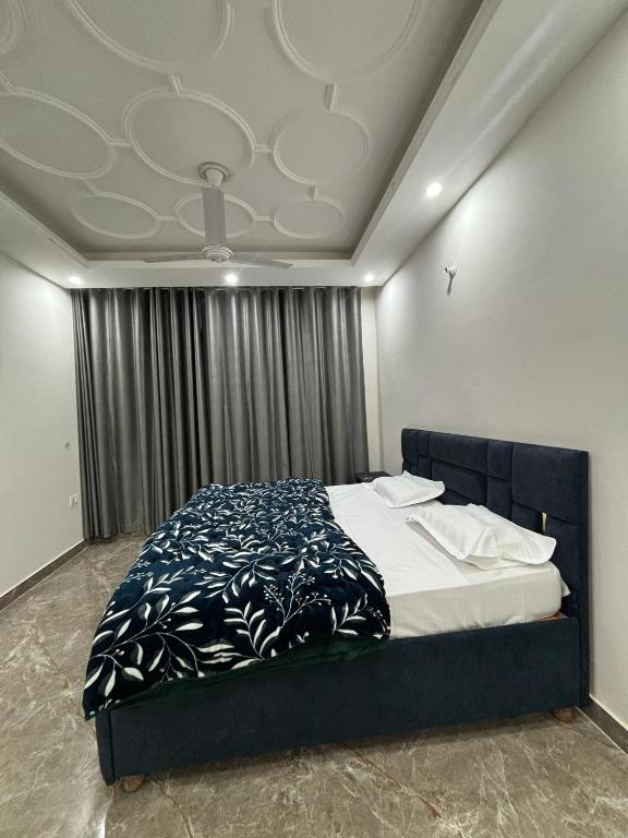 a bedroom with a bed with a blue and white comforter at shivoham Stays in Mājra