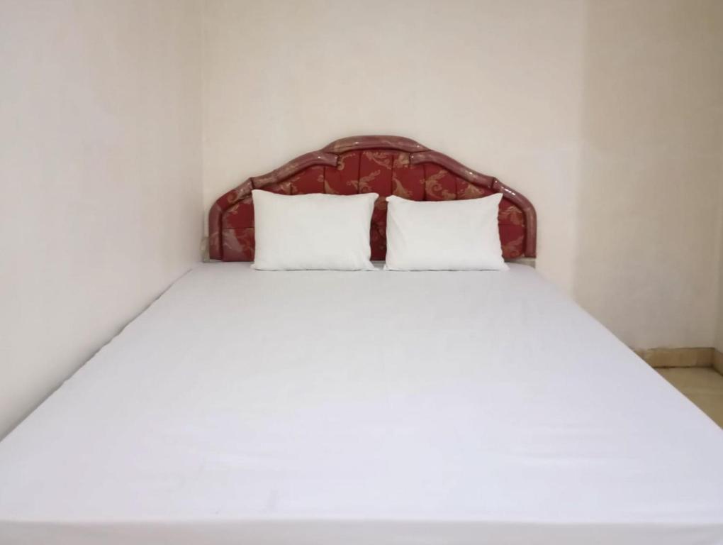 een bed met twee witte kussens in een kamer bij Hotel Intan Sampang Banyumas RedPartner 