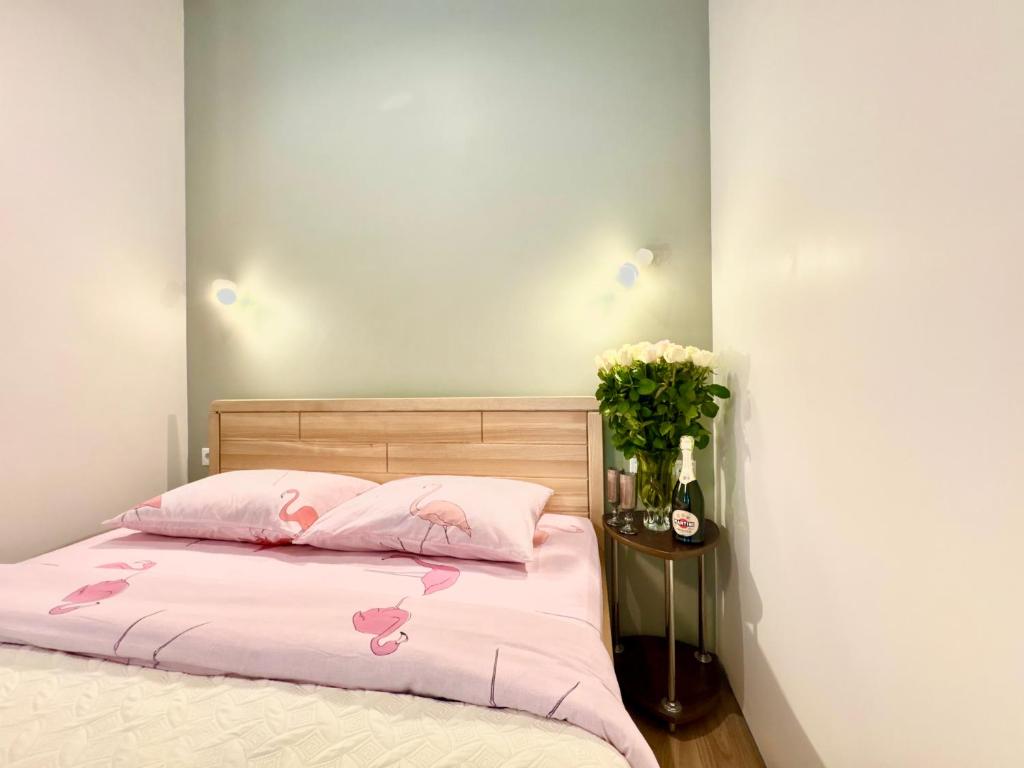 a bed with pink sheets and a vase of flowers at Lux Garden Appartments in Kharkiv