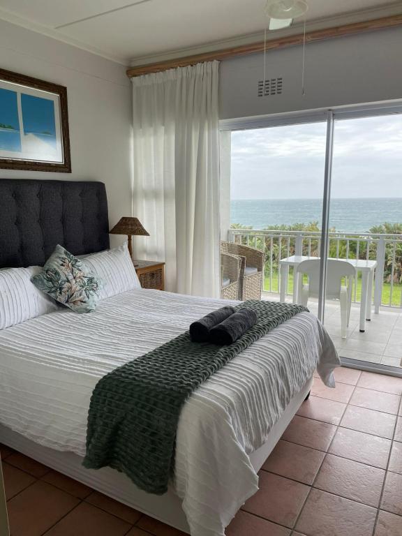 a bedroom with a bed and a view of the ocean at Jakaranda 22 apartment, Uvongo in Uvongo Beach