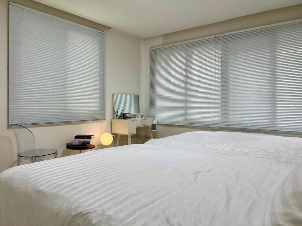 ein Schlafzimmer mit einem großen weißen Bett und Fenstern in der Unterkunft 부산 광안리 비앤비 스테이 in Busan