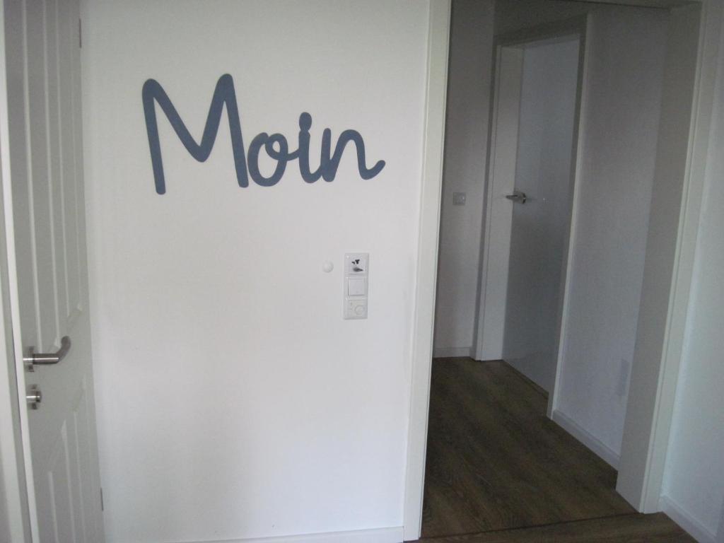 een witte muur met een bord erop in een gang bij Urlaub bei Alma in Wurster Nordseeküste