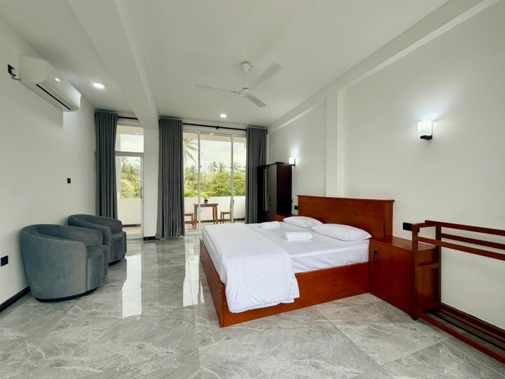 a bedroom with a bed and a couch and a chair at Turtle Bay Resort Hikkaduwa in Hikkaduwa
