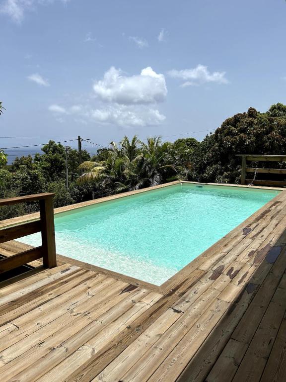 a swimming pool on a wooden deck with a bench at Kaz coco mango in Basse-Terre