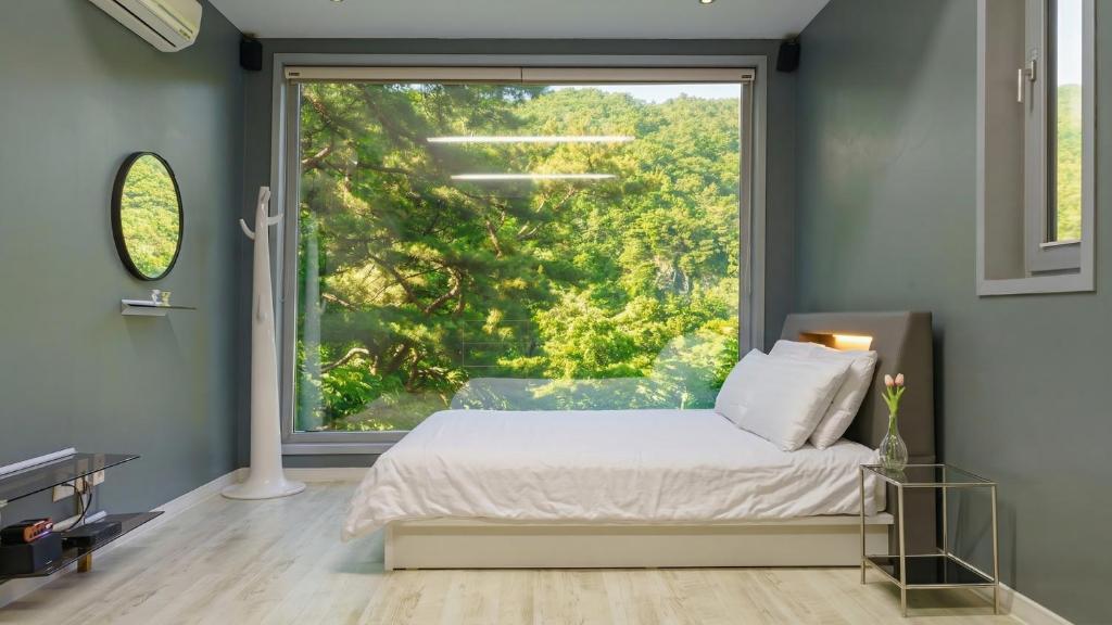 a bedroom with a bed and a large window at Hongcheon inmylife dokche pension in Hongcheon