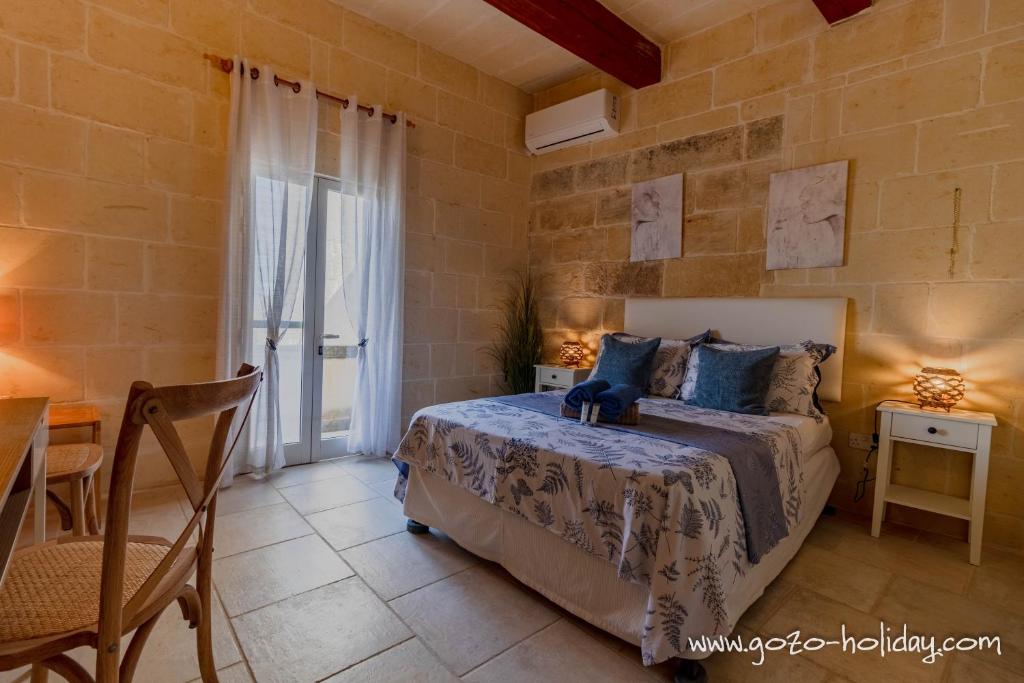 Un dormitorio con una cama, una mesa y una silla. en Tal Fjuri, en Xagħra