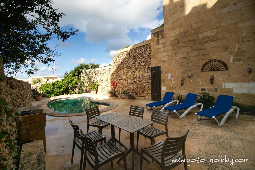 a patio with a table and chairs next to a pool at Tal Fjuri in Xagħra