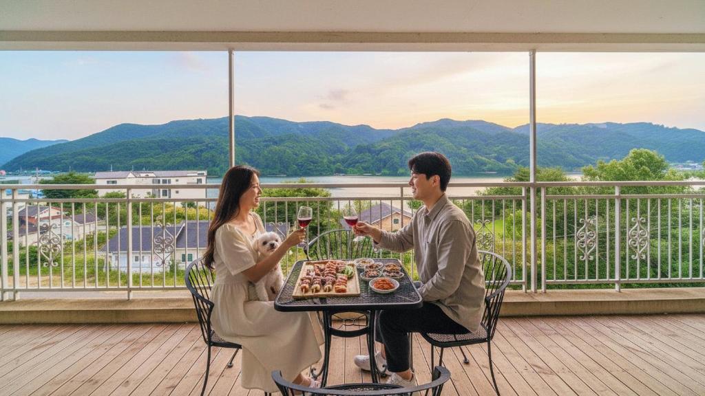 カピョンにあるGapyeong Club Fish Villas Pensionのワイングラスを持ってテーブルに座っている男女