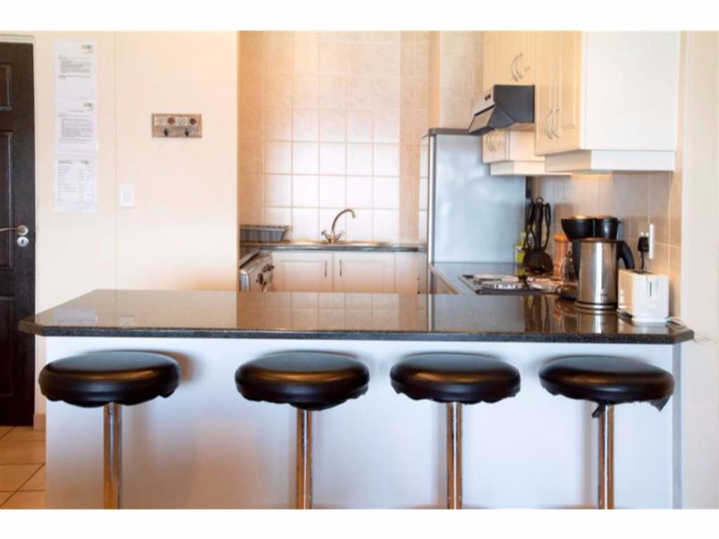 a kitchen with a counter with four bar stools at Balooga No. 36 in Margate