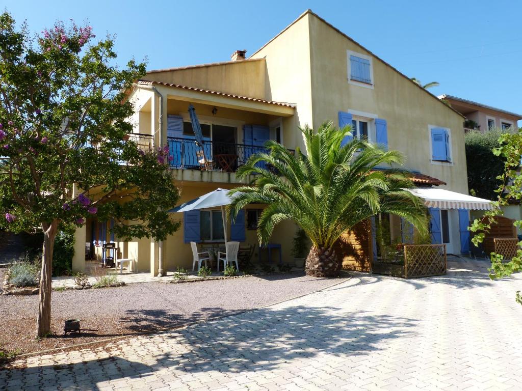 un bâtiment avec un palmier devant dans l'établissement Les Tourterelles, à Saint-Aygulf