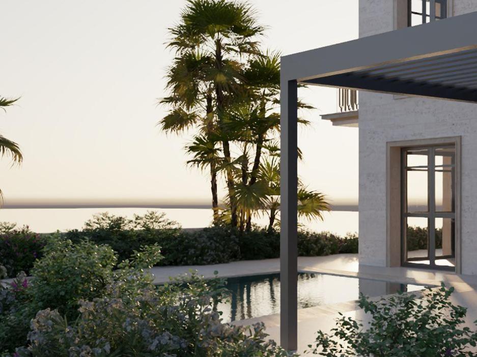 a house with a view of the ocean and palm trees at Lantana Villas & Hotel in Peyia
