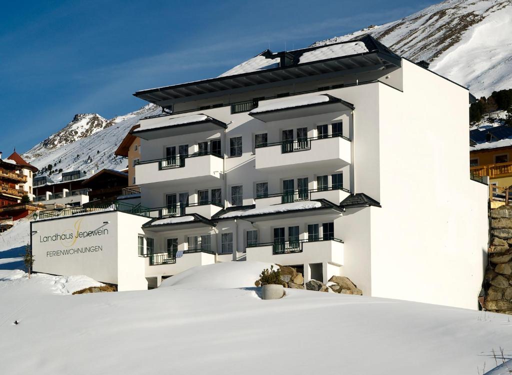 Ein weißes Gebäude im Schnee mit einem Berg in der Unterkunft Landhaus Jenewein in Obergurgl