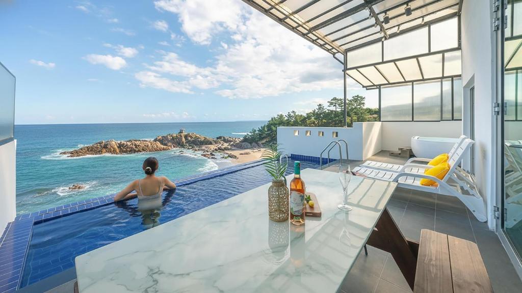 Una mujer en una piscina con vistas al océano en yeongdeok chaeumneul poolvilla, en Yŏngdŏk