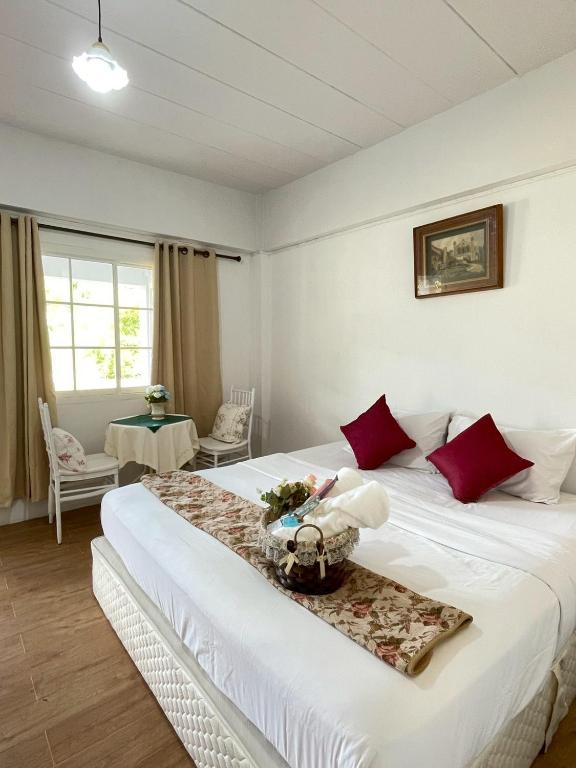 a bedroom with a large white bed with red pillows at Chermonné House เฌอมอญ 