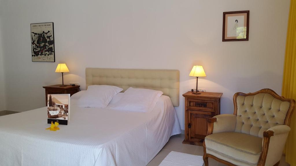 a bedroom with a white bed and a chair at Hotel Rural Can Maries in Puerto de San Miguel