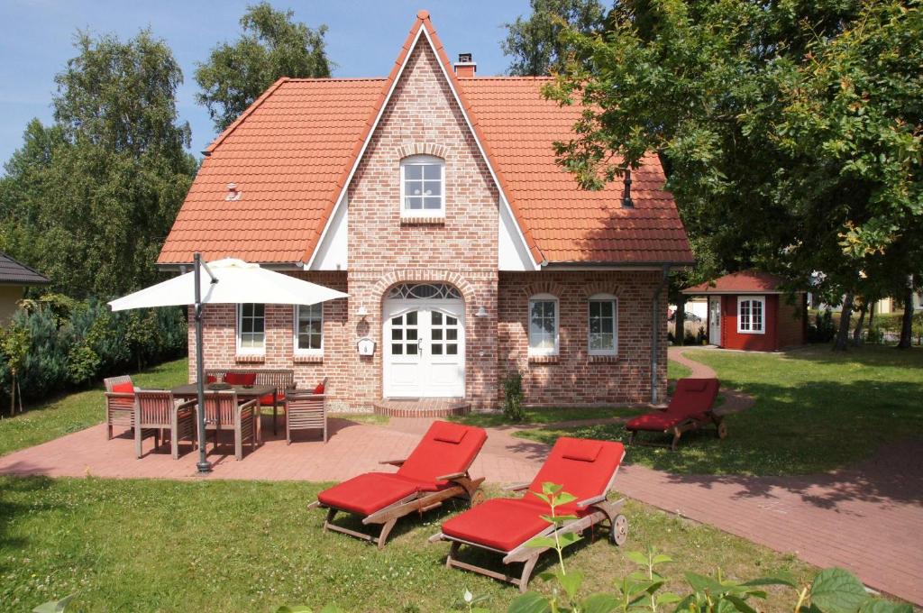 a brick house with red chairs and a table and an umbrella at Haus Eichenwald in Glowe