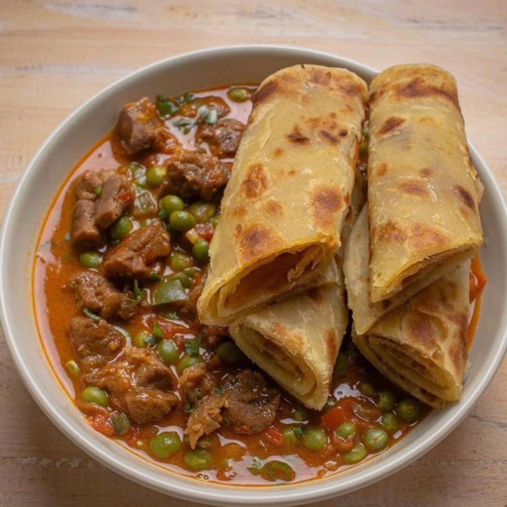 a plate of food with a bowl of food with meat and peas at TheChef NungwiBungalow in Kidoti