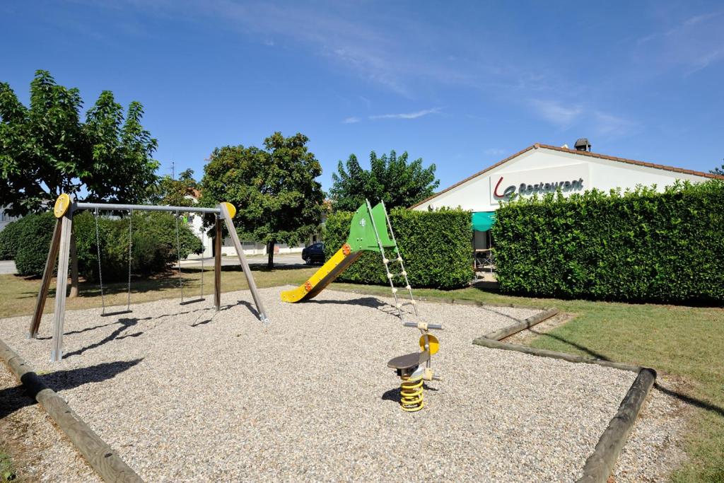 a playground with a slide and a green flag at Campanile Valence Sud in Valence