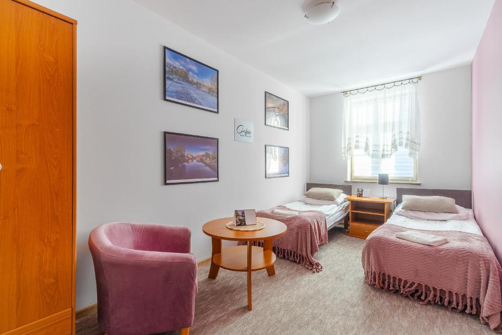 Habitación con 2 camas, silla y mesa. en Dom Pracy Twórczej, en Gryfice