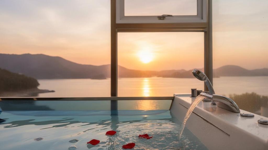 een badkamer met een bad en uitzicht op de oceaan bij Geoje Badageurigo Pension in Geoje 