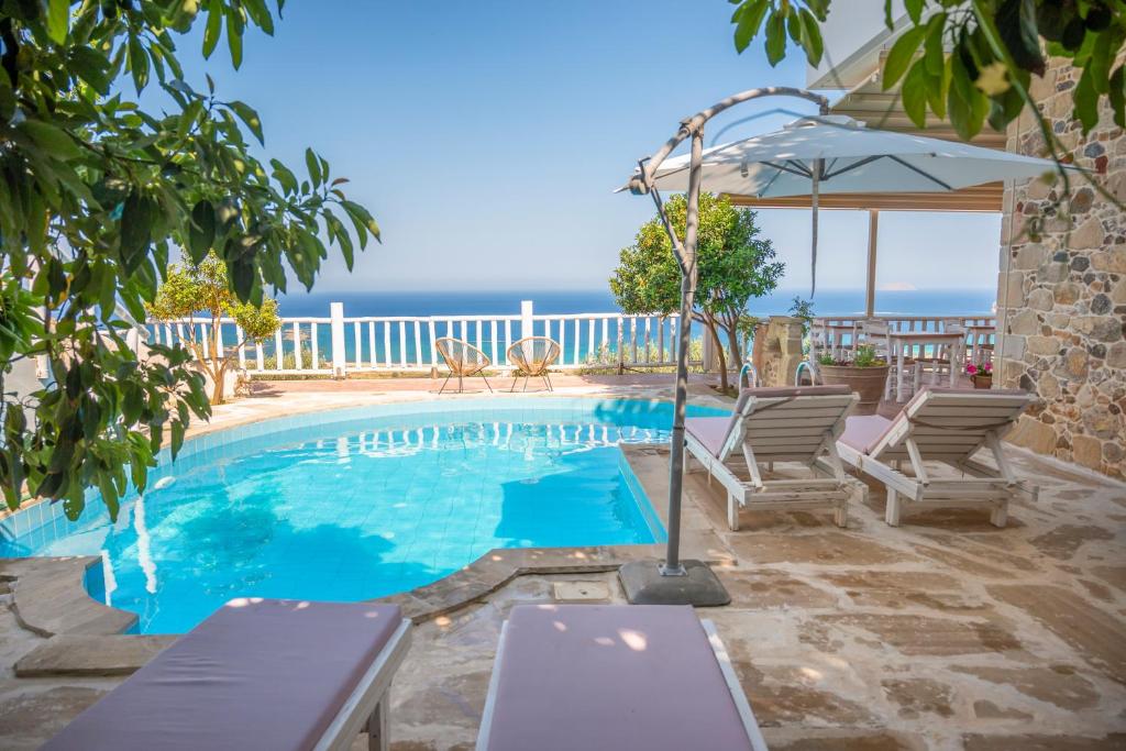 a swimming pool with two chairs and an umbrella at Elia in Kavoúsion