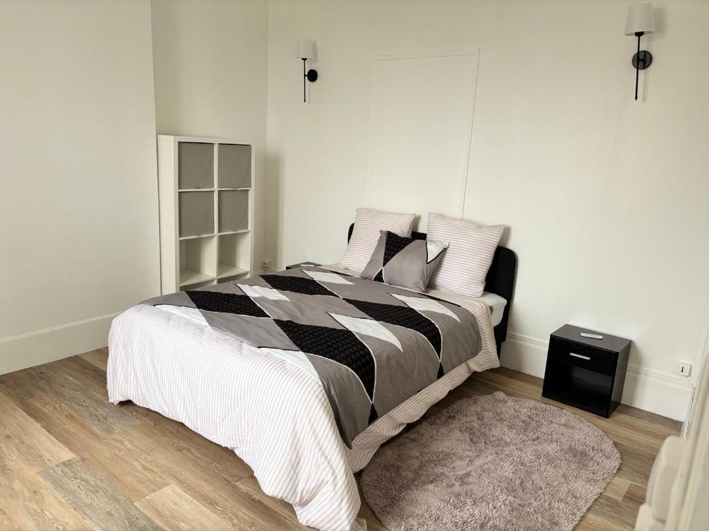 a bedroom with a bed with a black and white comforter at Super appartement in Malesherbes