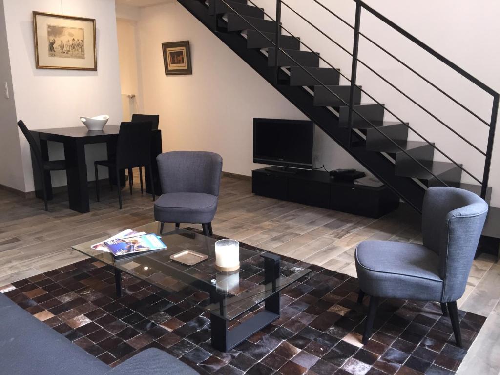 a living room with chairs and a table and stairs at Appartement Saint Thomas Prestige in Strasbourg