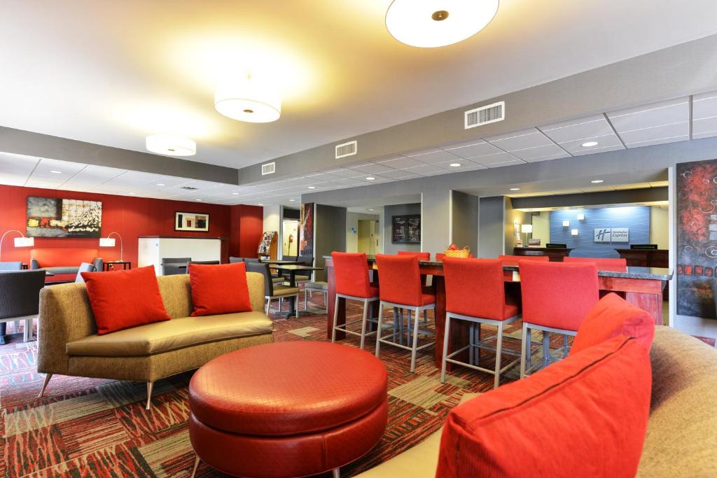 a hotel lobby with red chairs and a bar at Holiday Inn Express Painted Post by IHG in Painted Post