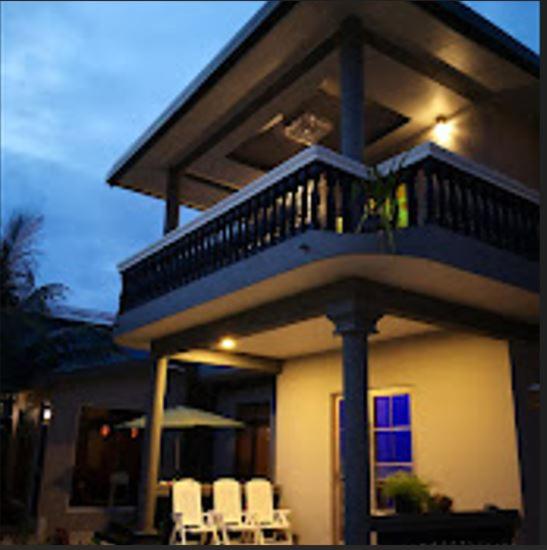 a house with a balcony and chairs in front of it at Ekefaru Inn in Viligili