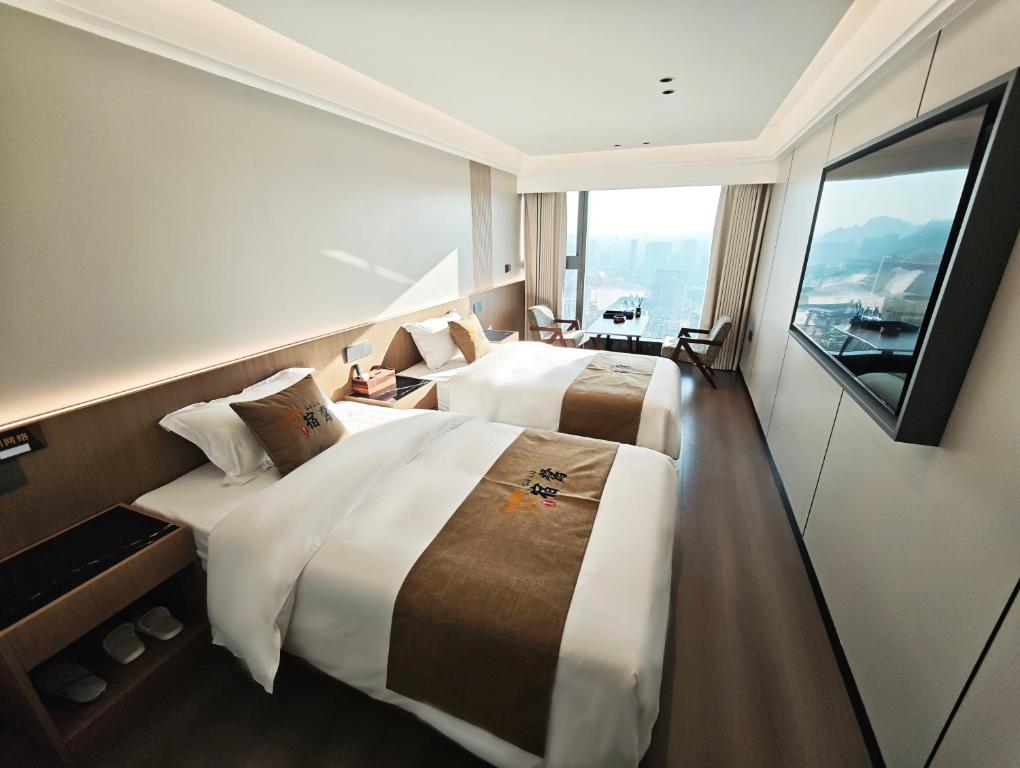 zwei Betten in einem Hotelzimmer mit großem Fenster in der Unterkunft Su Lu Hotel in Guiyang