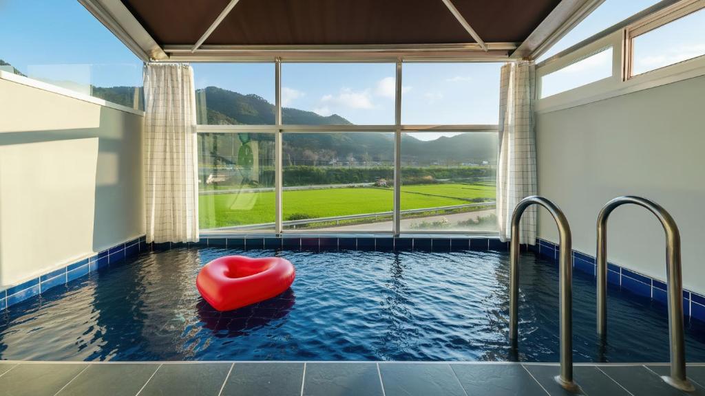 a hot tub with a red heart seat in a room with a window at Gyeongju Modern Pool Villa in Gyeongju