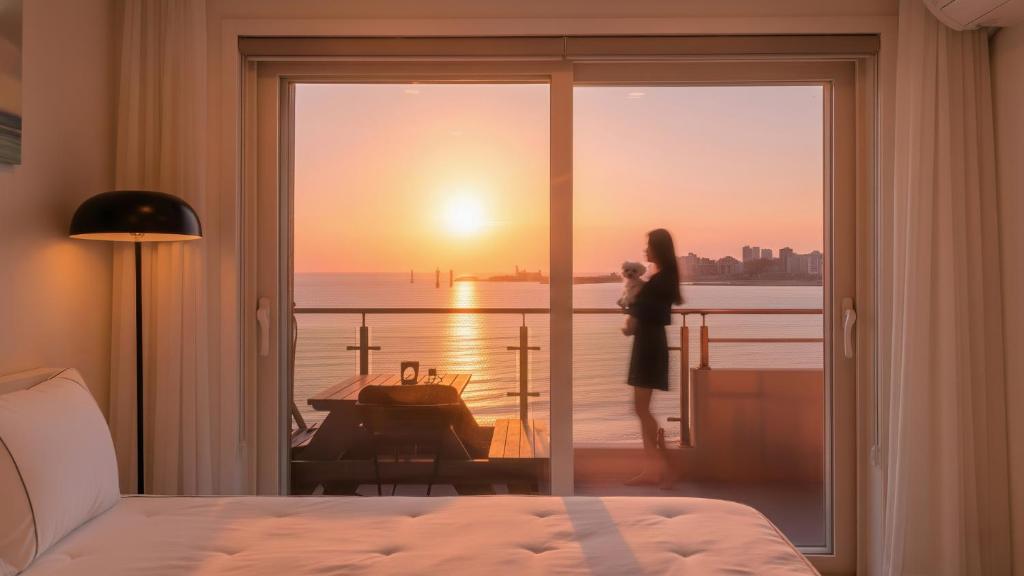 a woman standing on a balcony looking out at the sunset at Goseong Badasga per Osyeonbyu Pension in Goseong