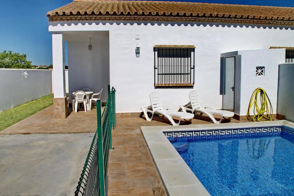 a villa with a swimming pool and a house at Chalet Arroyo Peñuelas 41 in Conil de la Frontera