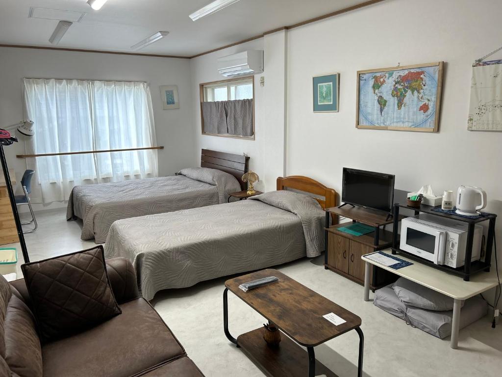 een woonkamer met twee bedden en een bank bij Accommodation Service B&B in Miyazaki