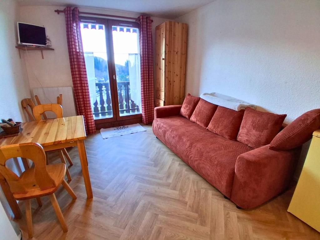 Studio SnowCarroz with a view for 4 people في Arâches-la-Frasse: غرفة معيشة مع أريكة حمراء وطاولة
