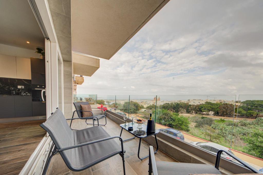 a balcony with a table and chairs and a large window at Ridge View Rooms - in a Shared Apartment - Sea Views in Mellieħa