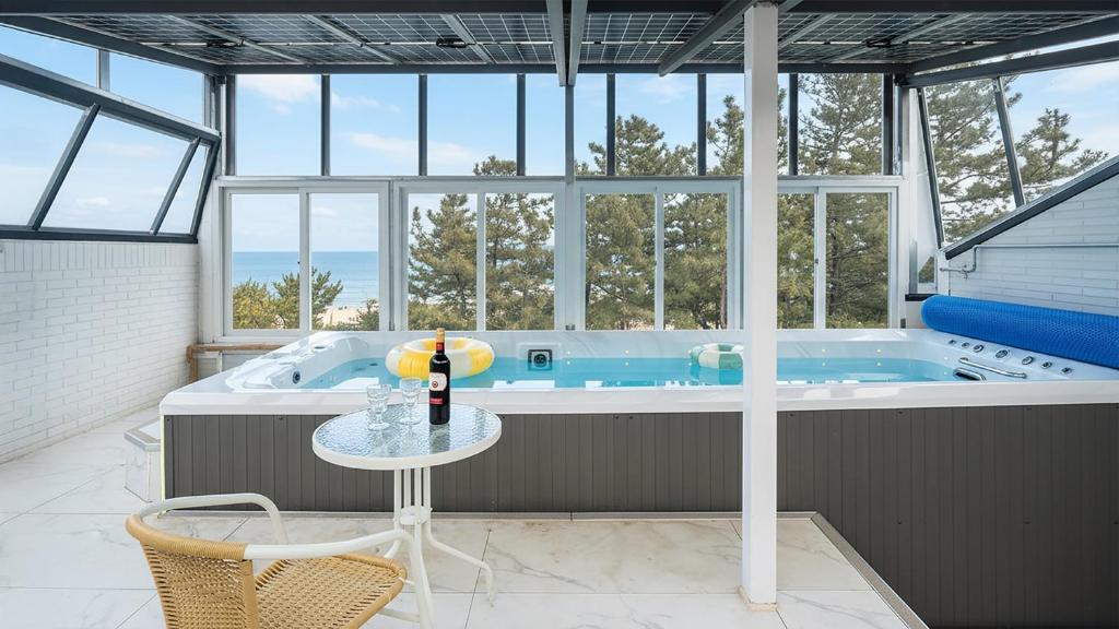 eine Whirlpool-Badewanne in einem Zimmer mit Tisch in der Unterkunft Samcheok Migaloo Pool Villa Pension in Samcheok