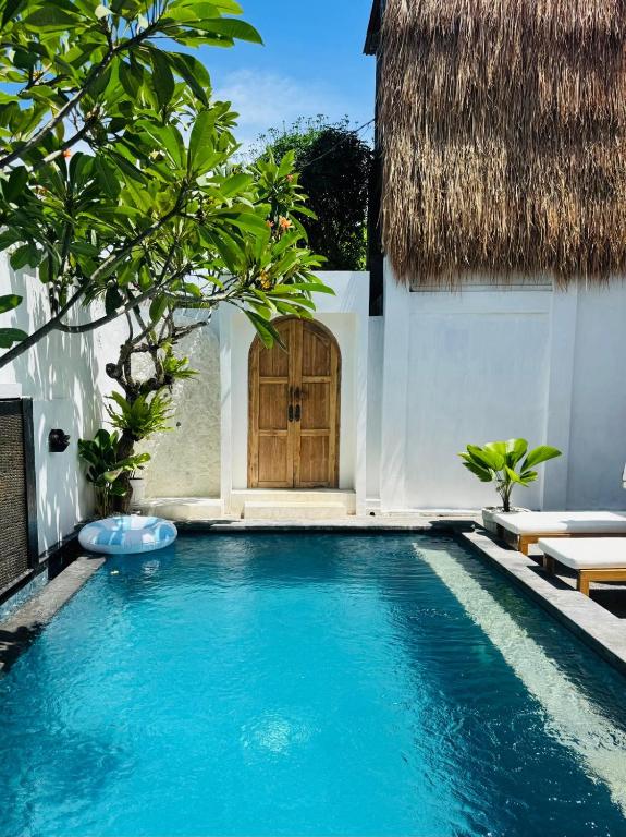 een zwembad voor een huis met een houten deur bij Gypsea Rest Villa in Nusa Lembongan