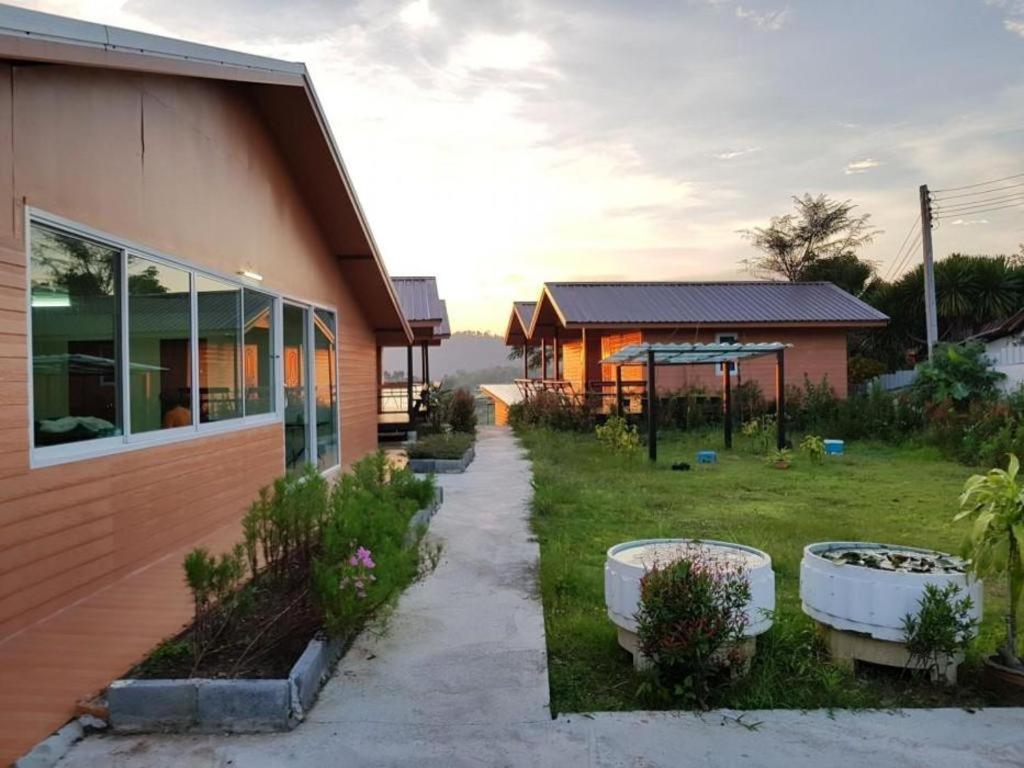 Jit Dee Home Khao Kho في كاو كو: منزل به زراعتان كبيرتان باللون الأبيض بجوار ساحة