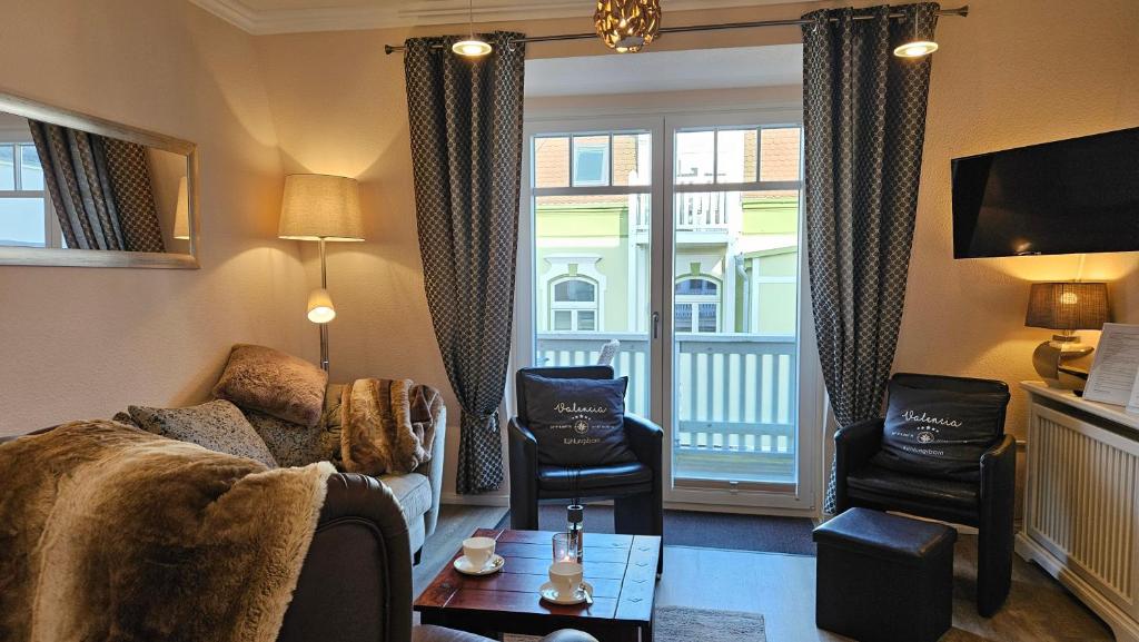 ein Wohnzimmer mit einem Sofa, Stühlen und einem Fenster in der Unterkunft FeWo Valencia Am Rosenhof - 5 Sterne DTV in Kühlungsborn