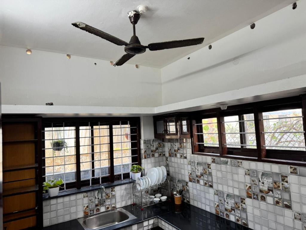 een badkamer met een plafondventilator en een wastafel bij White coral beach home in Alleppey