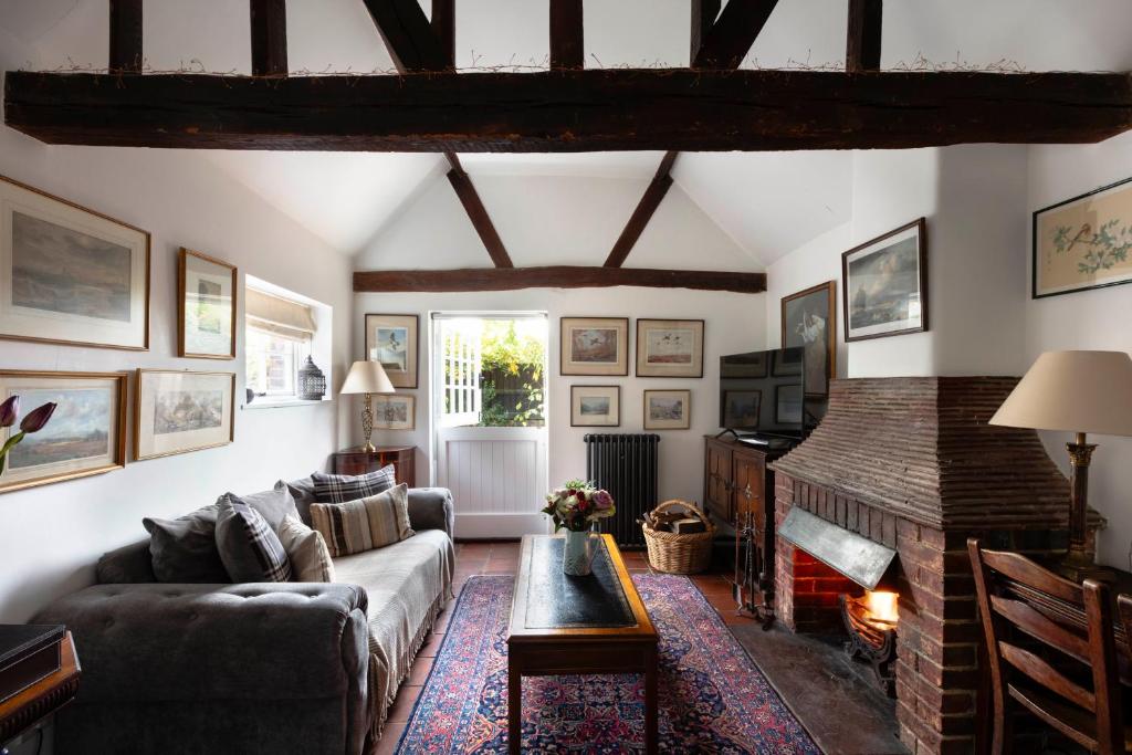 een woonkamer met een bank en een open haard bij The Cottage in Fernhurst