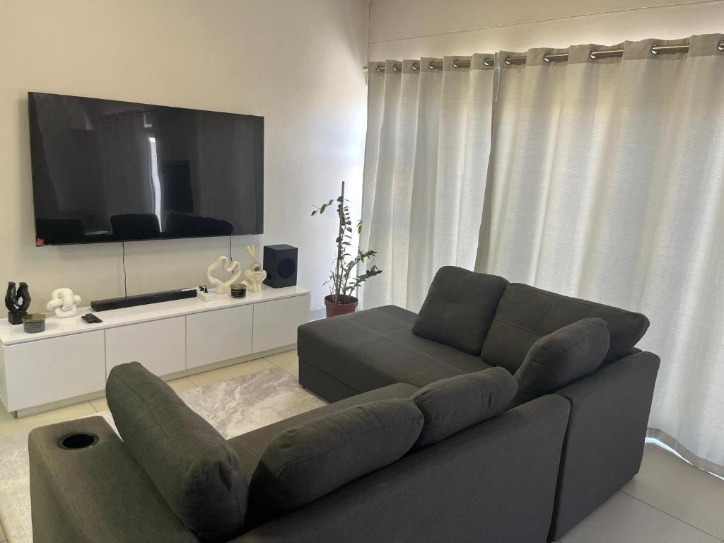 een woonkamer met een bank en een flatscreen-tv bij Modern Getaway in Rand Rifles