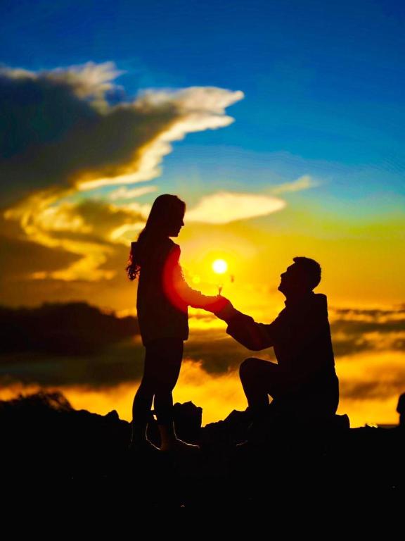 a man and a woman standing on top of a mountain at sunset at Isyana's Family Suites Batur View by EPS in Kubupenlokan