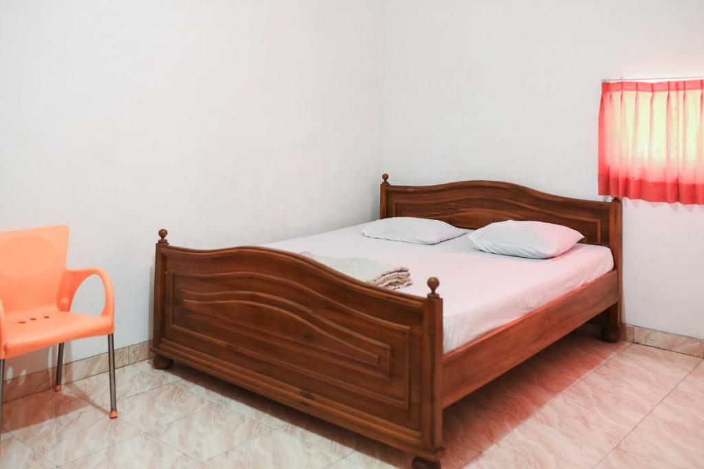 a bedroom with a wooden bed and a chair at Nirina Homestay Pringsewu Mitra RedDoorz in Margakaya