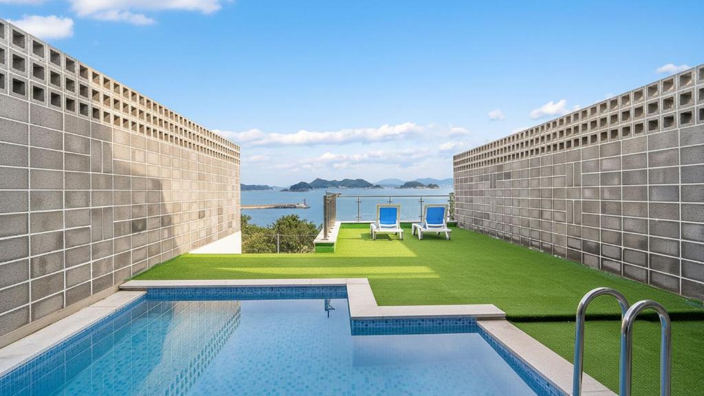 een zwembad tussen twee gebouwen met twee ligstoelen bij Yeosu Liposo Poolvilla in Yeosu